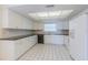 Well-lit kitchen featuring white cabinets, black countertops, and clean white tiled floors for a minimalist design at 739 Chesapeake Dr, Tarpon Springs, FL 34689