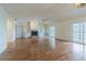 Open living room with hardwood floors, fireplace, built-in shelving, and sliding glass doors to a balcony at 739 Chesapeake Dr, Tarpon Springs, FL 34689