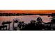 Tranquil waterfront view at dusk, featuring boat docks, palm trees, and the city lights across the water at 739 Chesapeake Dr, Tarpon Springs, FL 34689
