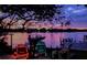 Tranquil waterfront view at twilight highlights lush trees, docks, and colorful Adirondack chairs at 739 Chesapeake Dr, Tarpon Springs, FL 34689