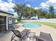 Beautiful backyard featuring a sparkling pool, mature trees, and comfortable lounge chairs at 800 Embassy Rd, Largo, FL 33771