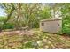 Beautiful backyard with mature trees providing ample shade, along with a shed, seating, and a grill at 8268 Garrison St, Spring Hill, FL 34606