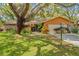 Beautiful exterior with mature trees, manicured lawn, and large driveway leading to the garage at 8268 Garrison St, Spring Hill, FL 34606