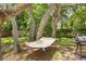 A cozy hammock is strung between mature trees with a grill nearby, creating a relaxing outdoor oasis at 8268 Garrison St, Spring Hill, FL 34606