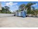 Spacious backyard with a blue shed, ample concrete space, and lush landscaping under a sunny sky at 8310 Pat Blvd, Tampa, FL 33615