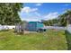 Backyard featuring a blue shed with a dog kennel, surrounded by green grass and foliage at 8310 Pat Blvd, Tampa, FL 33615