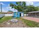 View of a backyard with a blue shed with open door, lawn, and brick patio at 8310 Pat Blvd, Tampa, FL 33615