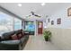 Comfortable living room featuring a dark leather sofa, tiled floors, and abundant natural light from large windows at 8310 Pat Blvd, Tampa, FL 33615