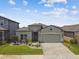 Landscaped home featuring a two-car garage, gray exterior paint, and manicured lawn at 9316 Crescent Ray Dr, Wesley Chapel, FL 33545