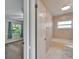 Hallway view into bathroom with neutral tile shower and bathtub combination with window at 9403 Bellhaven St, Temple Terrace, FL 33637