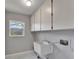 Functional laundry room with overhead cabinets, utility sink, and a window letting in natural light at 9403 Bellhaven St, Temple Terrace, FL 33637