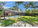 A screened-in pool with a large grassy area and concrete patio, surrounded by mature trees and landscaping at 9403 Bellhaven St, Temple Terrace, FL 33637