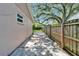 A concrete pathway lined by a wood fence and mature trees, providing privacy and a natural feel at 9403 Bellhaven St, Temple Terrace, FL 33637