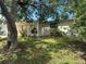 Landscaped front yard with a mature tree shading the house, providing a cool and inviting curb appeal at 9411 Rainbow Ln, Port Richey, FL 34668