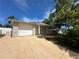Charming one-story home featuring an attached garage and well-maintained front yard with mature trees at 9411 Rainbow Ln, Port Richey, FL 34668