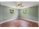 Comfortable bedroom featuring wood floors, a ceiling fan, and dual windows at 10039 Old Hickory Ln, Port Richey, FL 34668