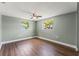 Relaxing bedroom with wood floors, a ceiling fan, and natural light from two windows at 10039 Old Hickory Ln, Port Richey, FL 34668