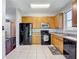 Functional kitchen features oak cabinets, tile floors, and black appliances at 10323 Birdwatch Dr, Tampa, FL 33647