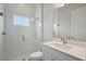 Bathroom with glass shower enclosure, bright window and vanity with white sink and stone counter at 11622 Gleaming Ter, Venice, FL 34293