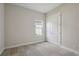Carpeted bedroom with double-door closet, neutral walls, and bright window with manicured landscaping view at 11622 Gleaming Ter, Venice, FL 34293