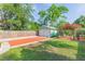 Expansive backyard featuring lush lawn, a pergola adorned with flowers, and a detached garage at 1202 E Mohawk Ave, Tampa, FL 33604