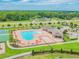 Expansive community pool area with lounge chairs, tables, and a clubhouse, all surrounded by lush landscaping and recreational facilities at 12351 Nouveau Ave, Spring Hill, FL 34610