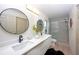 Bright bathroom featuring dual sinks, round mirrors, and a glass-enclosed shower at 13203 Royal George Ave, Odessa, FL 33556