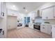 Bright kitchen featuring modern white cabinetry, stainless steel appliances, and light wood flooring at 13203 Royal George Ave, Odessa, FL 33556