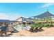 Resort-style swimming pool with plenty of seating, palm trees, sun shades and a modern clubhouse in the background at 13644 Canyon Ridge Rd, Spring Hill, FL 34610