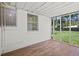 Bright screened in porch with wood-look flooring, white walls, and views of the backyard and surrounding trees at 1512 Hillside Dr, Tampa, FL 33610