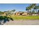 View of the clubhouse from the street on a sunny day with palm trees at 1605 Mission Hills Blvd # D5, Clearwater, FL 33759