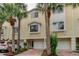 Two-story townhome exterior with palm trees, brick pavers, and white garage doors at 163 Brent Cir, Oldsmar, FL 34677