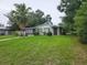Charming single-story home featuring a cozy front porch, mature trees, and a spacious lawn at 1711 E Poinsettia Ave, Tampa, FL 33612