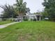 Charming single-story home featuring a cozy front porch, mature trees, and a spacious lawn at 1711 E Poinsettia Ave, Tampa, FL 33612