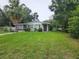 Charming single-story home featuring a cozy front porch, mature trees, and a spacious lawn at 1711 E Poinsettia Ave, Tampa, FL 33612