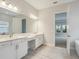 Bathroom featuring double sinks, white cabinetry, and a doorway with a view to another bedroom at 17555 Glistening Ct, Venice, FL 34293