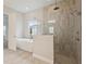 Elegant bathroom featuring a soaking tub, glass shower, and neutral tile at 17555 Glistening Ct, Venice, FL 34293