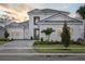 Beautiful home with three-car garage, brick driveway, and manicured front yard at sunset at 17555 Glistening Ct, Venice, FL 34293