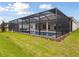 Backyard view of a screened-in pool and spa from the grassy lawn at 17555 Glistening Ct, Venice, FL 34293