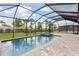 Screened-in pool with spa and brick paver decking surrounded by lush landscaping at 17555 Glistening Ct, Venice, FL 34293
