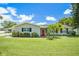 Charming home featuring a well-manicured lawn, a bright red front door, and lovely landscaping at 1857 N Belleair N Rd, Clearwater, FL 33764