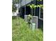 View of a home exterior with a central air conditioning unit sitting in overgrown grass at 1935 Oxnard Ct, Tampa, FL 33612