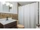 Cozy bathroom featuring a dark vanity and a shower with modern tile accents and a clean white shower curtain at 1949 Kings Hwy, Clearwater, FL 33755