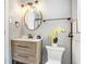 Modern bathroom with wood vanity, round mirror, stylish lighting, and pristine white fixtures create a spa-like retreat at 201 83Rd N Ave, St Petersburg, FL 33702