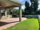 A brick patio with a pergola and well-manicured lawn surrounded by a white picket fence and lush landscaping at 20101 Oakflower Ave, Tampa, FL 33647