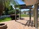 Covered brick patio showcasing a pergola with fire pit, palm trees, and a white picket fence at 20101 Oakflower Ave, Tampa, FL 33647