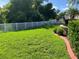 Green backyard featuring lush lawn and landscaping with a white picket fence at 20101 Oakflower Ave, Tampa, FL 33647