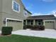 Two-story home featuring a lush green lawn, meticulously trimmed shrubs, and a convenient three-car garage at 20101 Oakflower Ave, Tampa, FL 33647