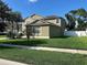 Green lawn surrounds this two-story home, complemented by a white fence on the rear side at 20101 Oakflower Ave, Tampa, FL 33647
