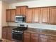 Stainless steel oven with a gas range and microwave in a kitchen with wooden cabinets and granite countertops at 20101 Oakflower Ave, Tampa, FL 33647